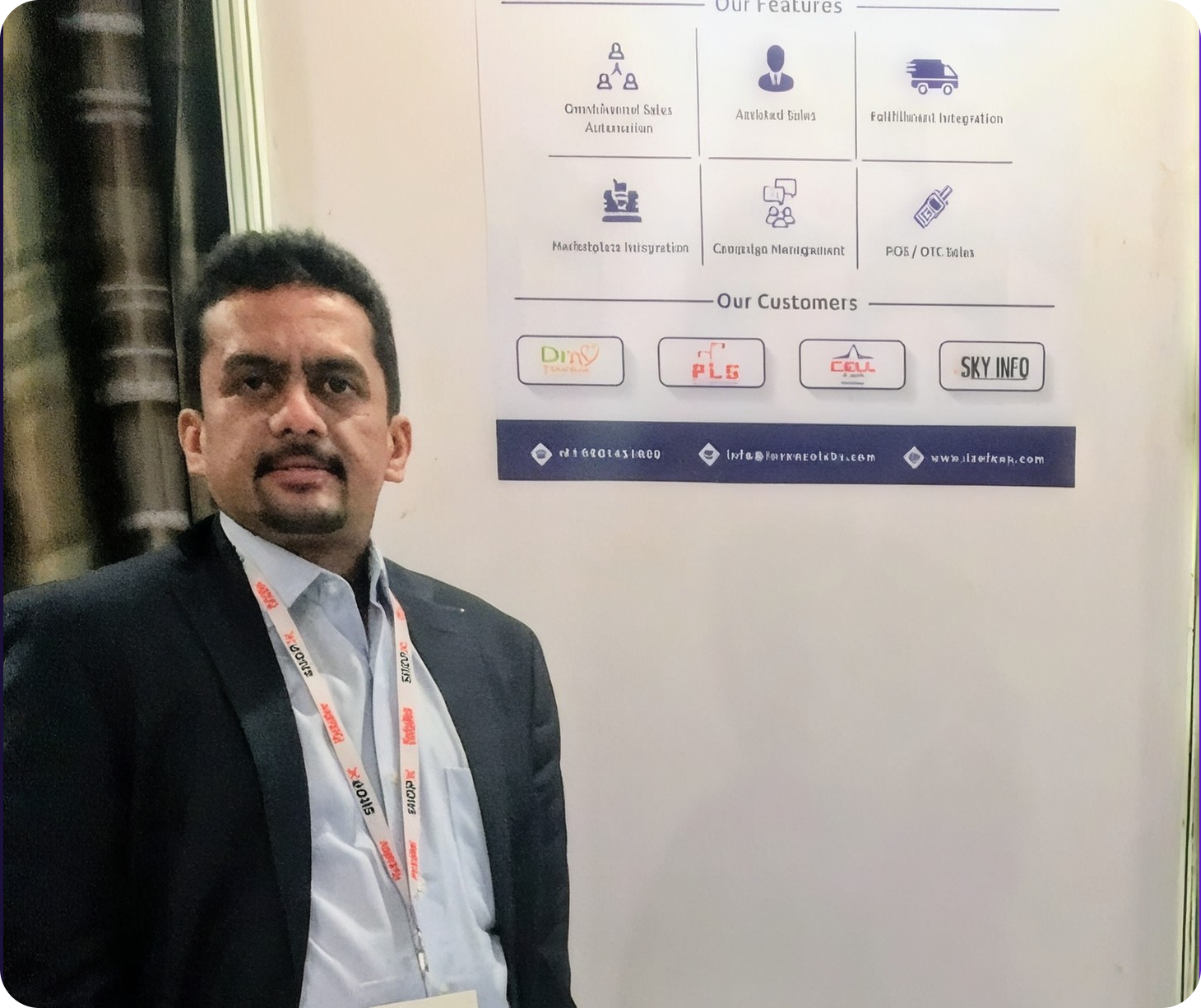 An Invenzo Labs team member standing at the IREC 2019 exhibition stand, in front of a screen showing the product's feature set.
